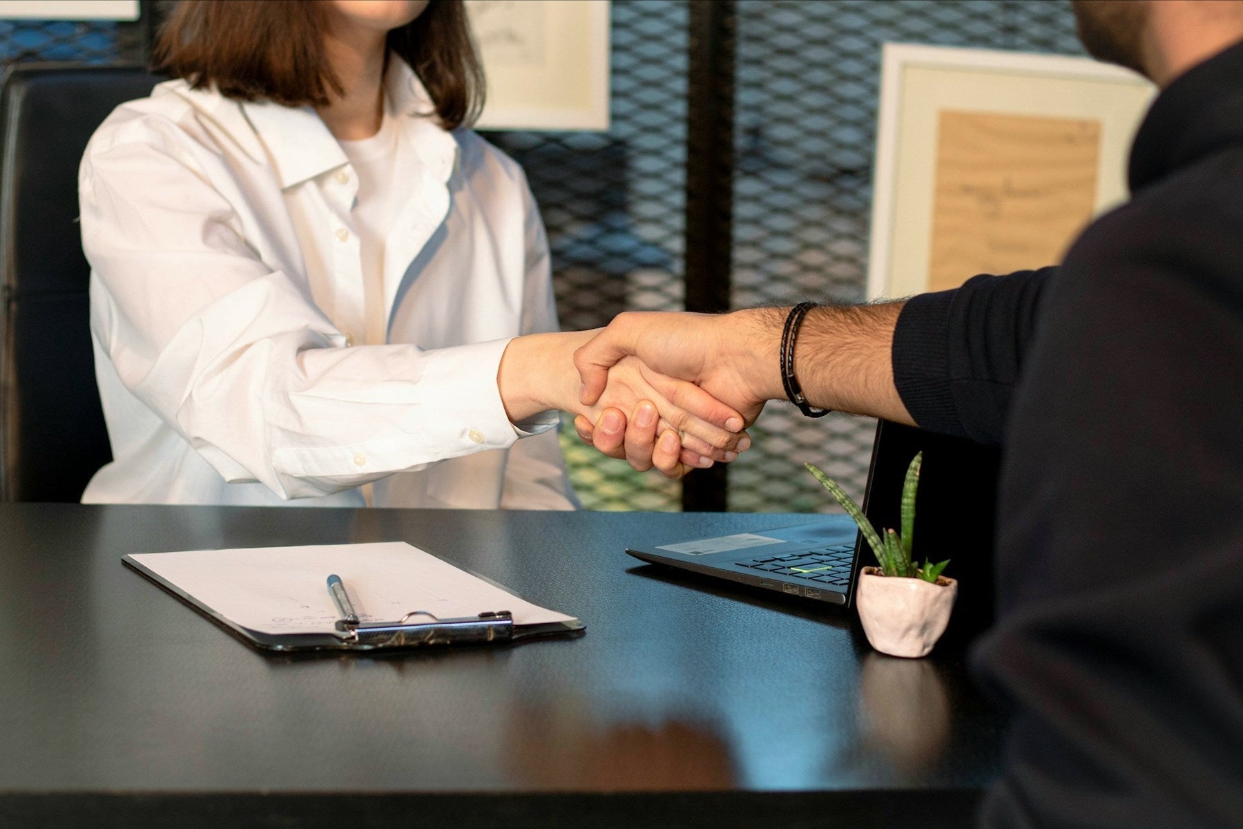 A woman shaking hands with her boss in a professional office setting