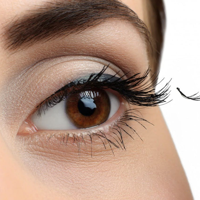 Girl putting eyelashes on her eye