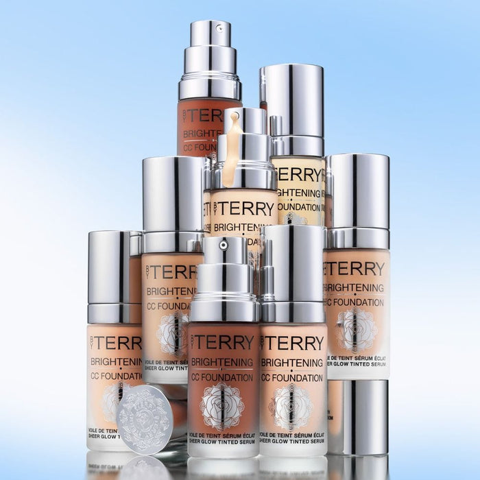 By Terry Brightening CC Foundation stylized bottles of various shades with blue background