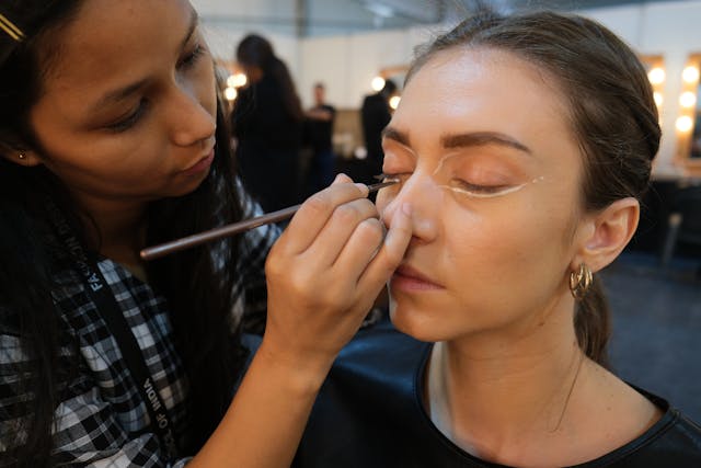 Makeup artist applying eye product to talent in green room
