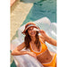 Natura Bisse Diamond Luminous Tinted UV Defense SPF40 Model holding in pool wearing golden orange bathing suit