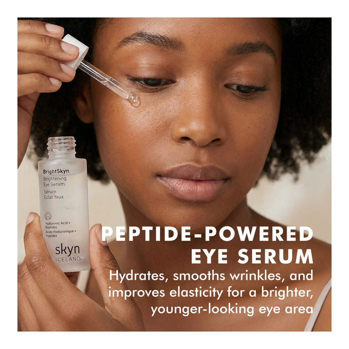 Skyn Iceland Brightening Eye Serum main benefits text under model applying product around her eye
