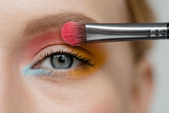Close-up of a brush applying colorful eyeshadow to the eyelid