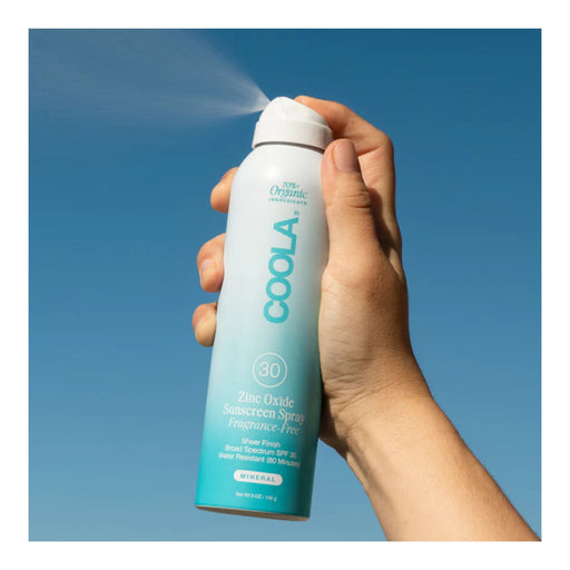 Coola Mineral Sunscreen Spray SPF 30 Fragrance Free 5oz being sprayed in the air against a blue background
