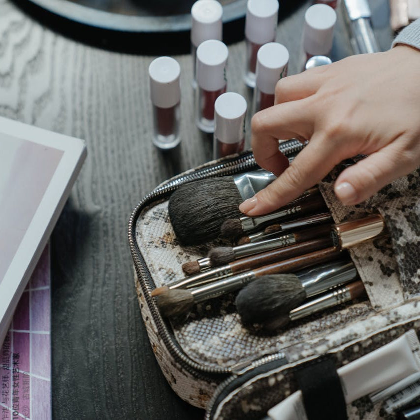 Hand adjusting a makeup brush in a beauty tool kit