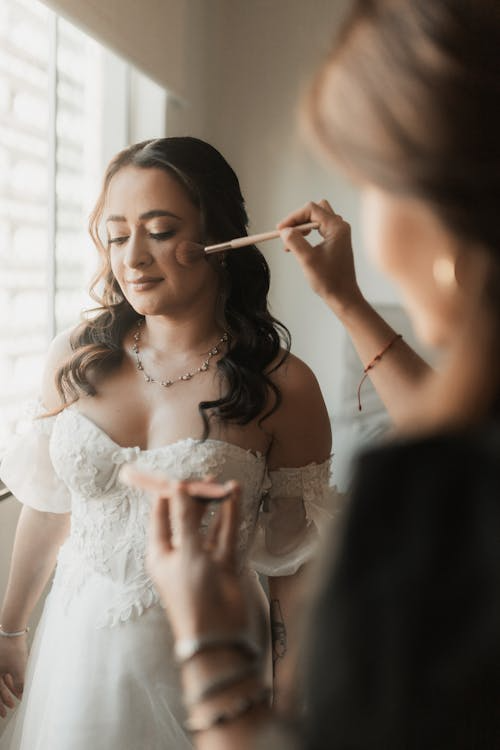 Makeup artist applying blush on bride’s cheek