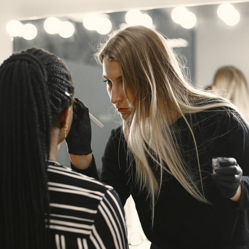 Makeup artist working on a client in front of a well-lit vanity
