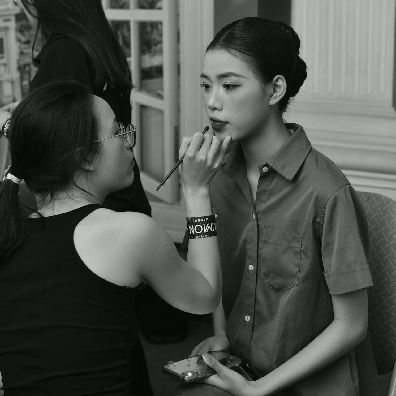Makeup artist using a brush to apply lipstick to a model