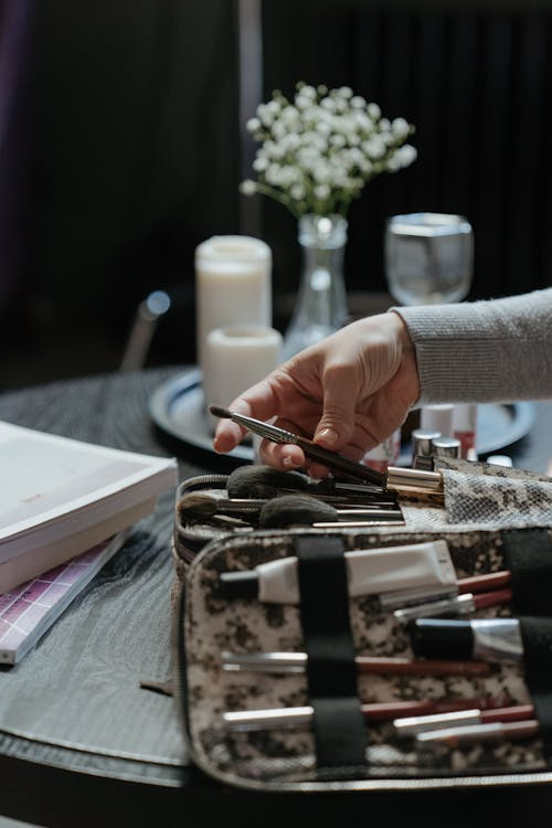 Person organizing makeup brushes in a tool kit