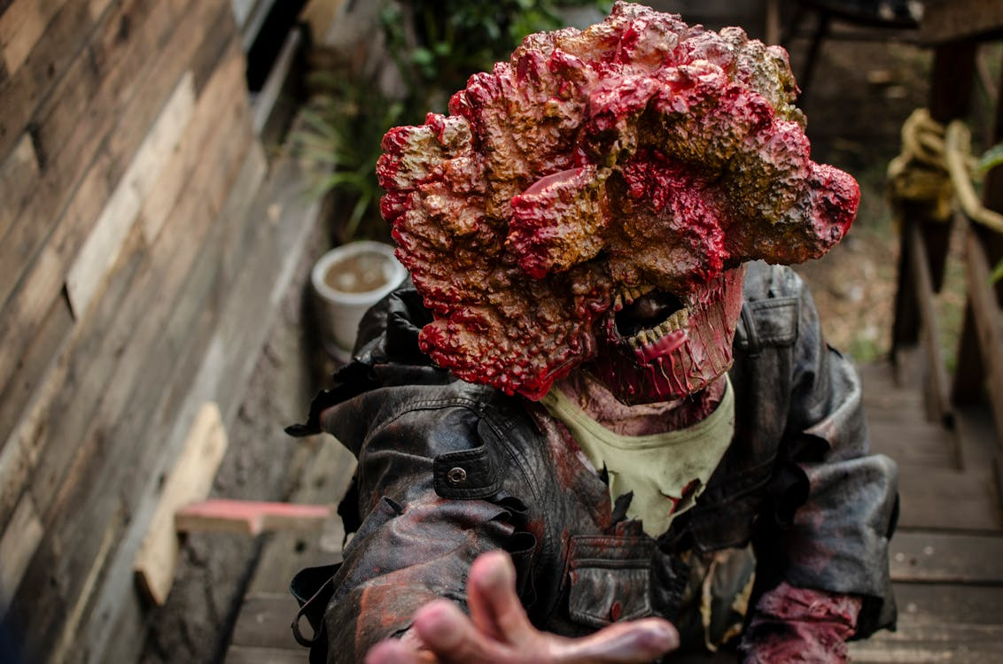 A person dressed in fleshy prosthetics, costumed as a zombie