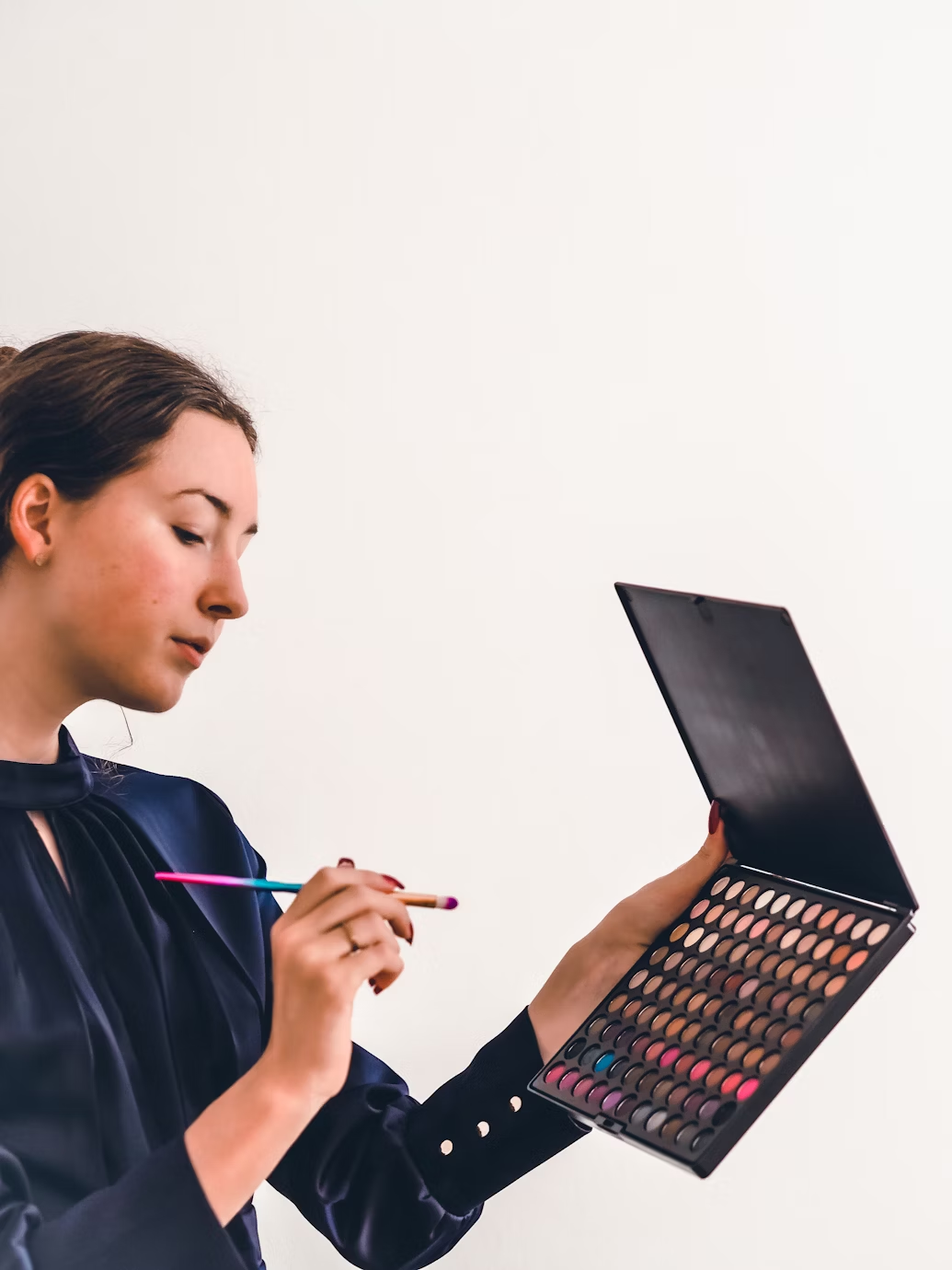 Professional makeup artist holding a brush poised over a colorful palette