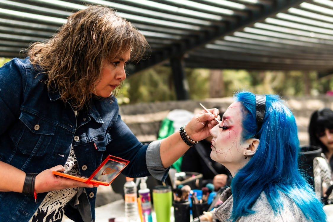 Professional makeup artist working on a client with blue hair