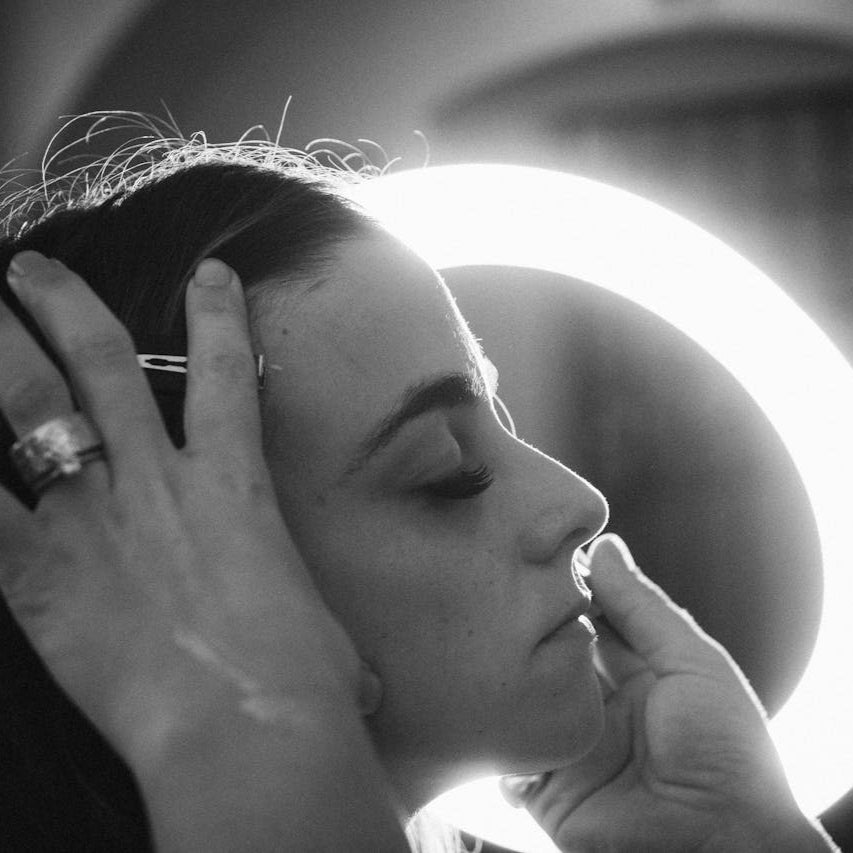 a makeup artist applying makeup to a client next to a professional makeup light