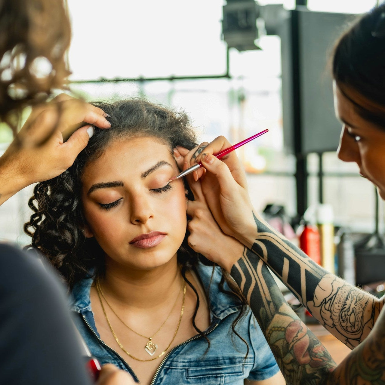 Woman getting her makeup done by two makeup artists